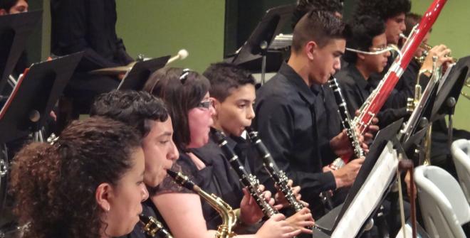 Niños con uniforme de color negro, tocando instrumentos de viento