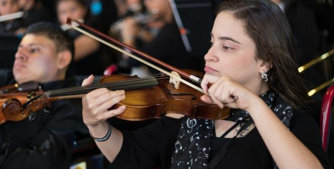 Niña tocando violín en una presentación en vivo.
