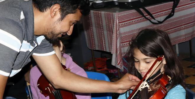 Profesor de violín le ayuda a niña estudiante