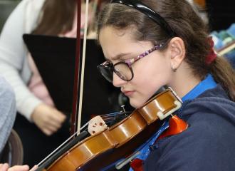 Niña toca violín durante una presentación