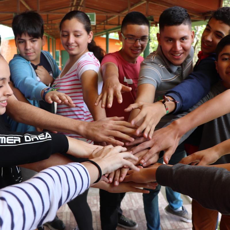 Personas jóvenes juntan las manos en celebración grupal